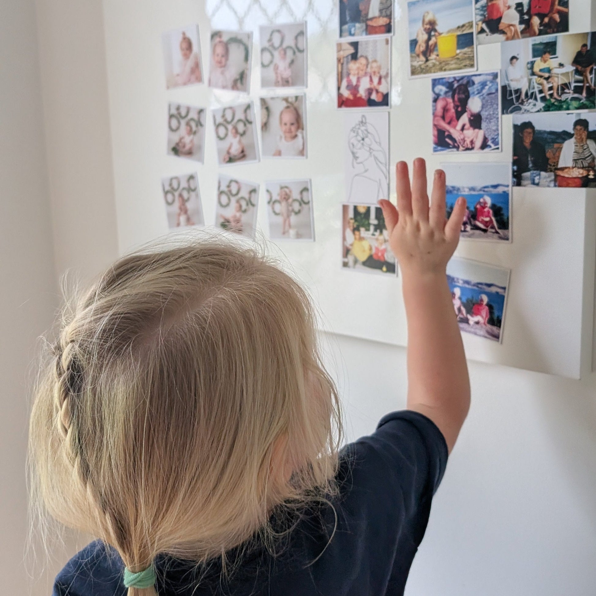 Little girl interacting with magnetic photos attached to white board